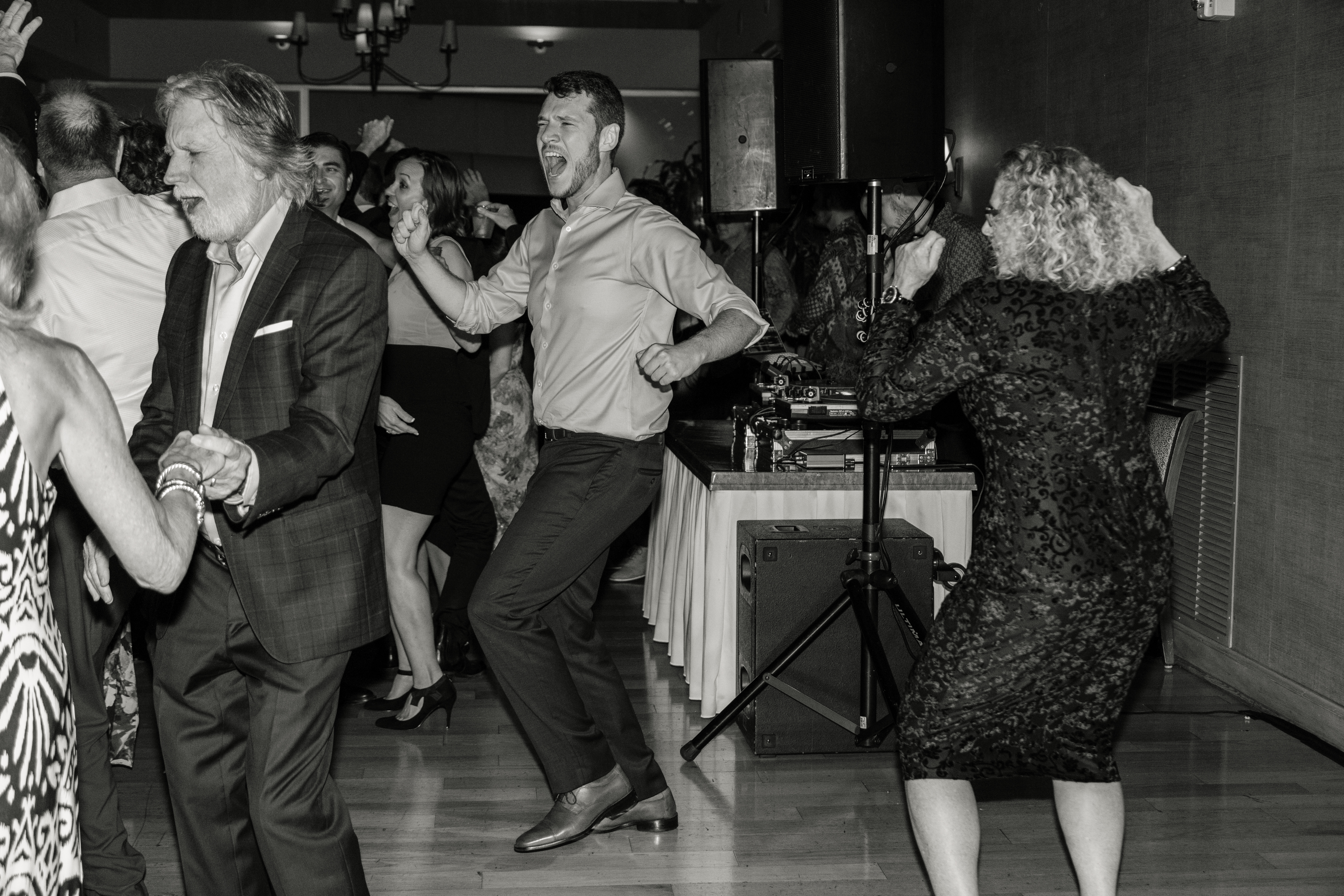 Black and white couples slow dancing under reception lights