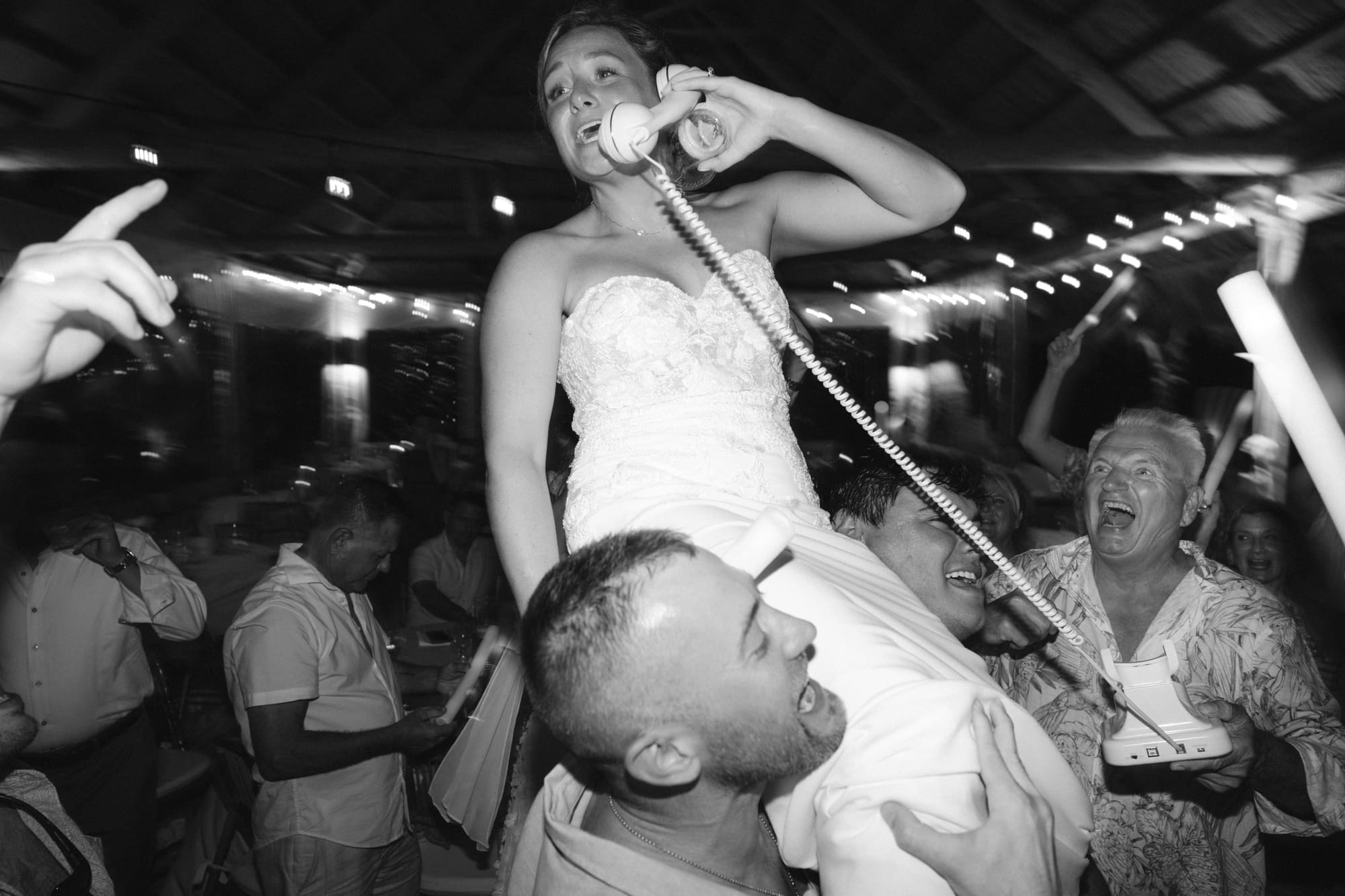 Bride lifted by groomsmen on the dance floor, black and white