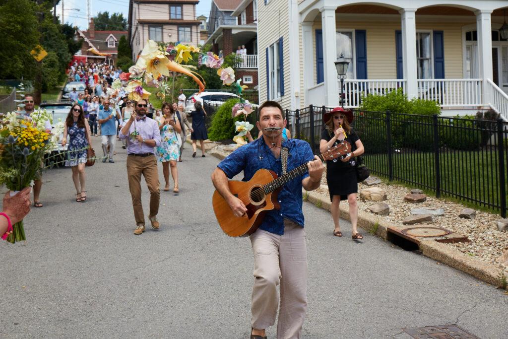Costumed parade with musicians and tall puppets honoring the couple